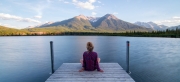 Eine Frau sitzt auf einem Steg und schaut hinaus auf den See