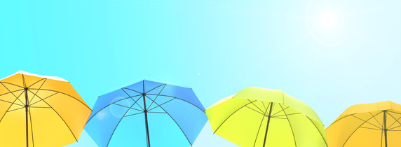 Vier Sonnenschirme in Gelb, Grün und Blau vor einem strahlenden Sommerhimmel