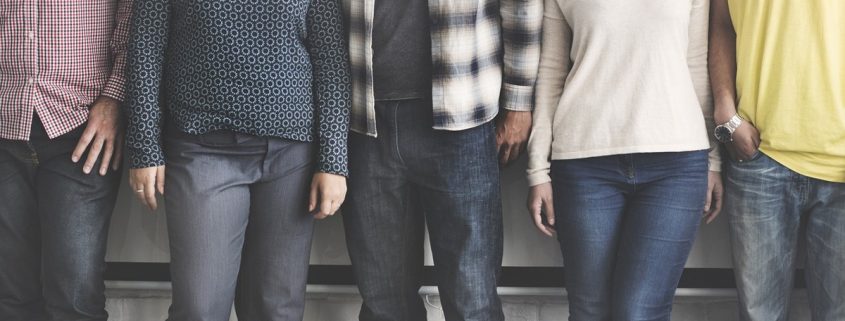 5 Personen stehen eng neben einander vor einer weißen Wand