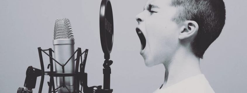 Ein Bub schreit in ein Mikrophon