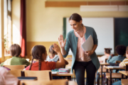 Lehrerin in eine Klasse, die mit einer Schülerin High Five gibt.