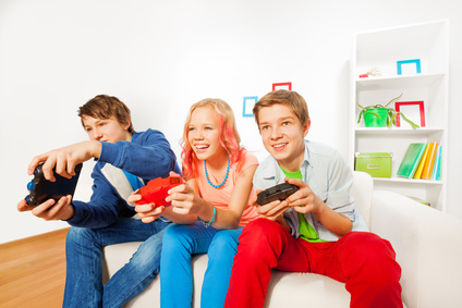 Ein Mädchen und zwei Burschen mit Joysticks spielen ein Videospiel
