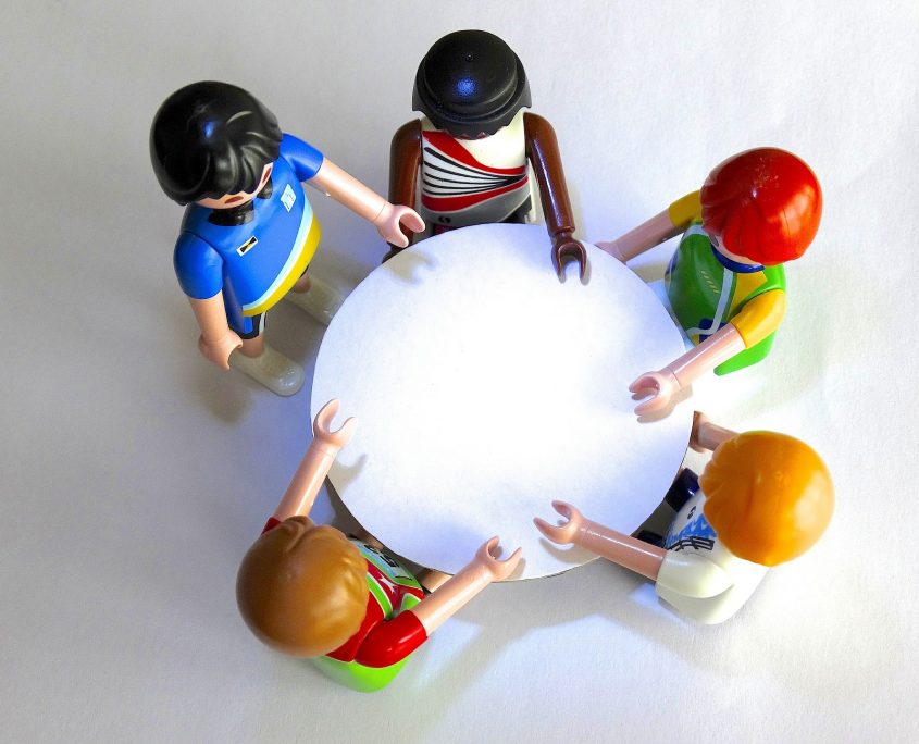 Playmobil-Figuren stehen um einen runden Tisch