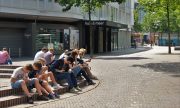 Kinder und Erwachsene sitzen auf einem öffentlichen Platz und starren in ihre Handys